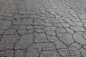 Cracked asphalt pavement in a parking lot, top angle.