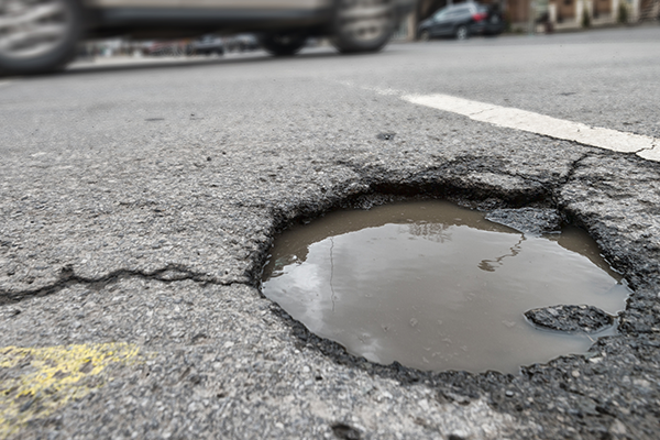 Asphalt pothole in a parking lot.