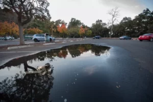 Large puddle caused by poor drainage on asphalt parking lot.