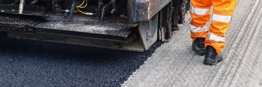 Asphalt paving contractors paving blacktop on a resurfaced parking lot.